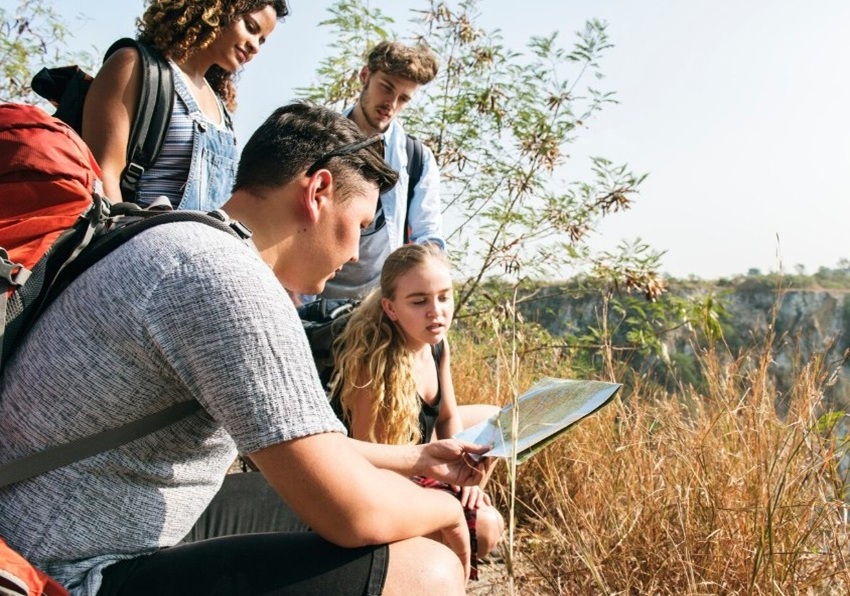Imagen de cuatro personas mirado un mapa en medio del campo